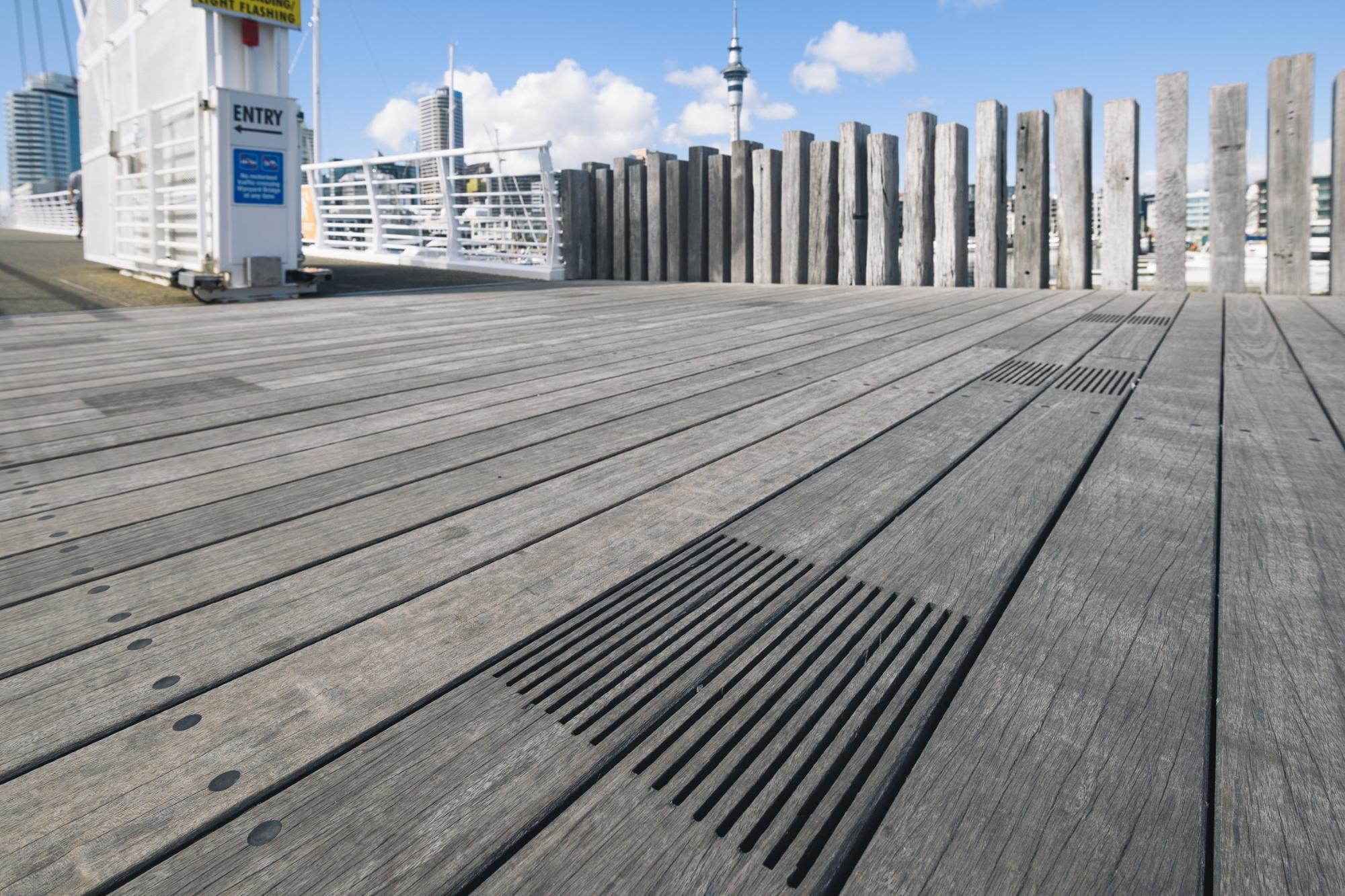 A wooden boardwalk with a wooden pole fence behind