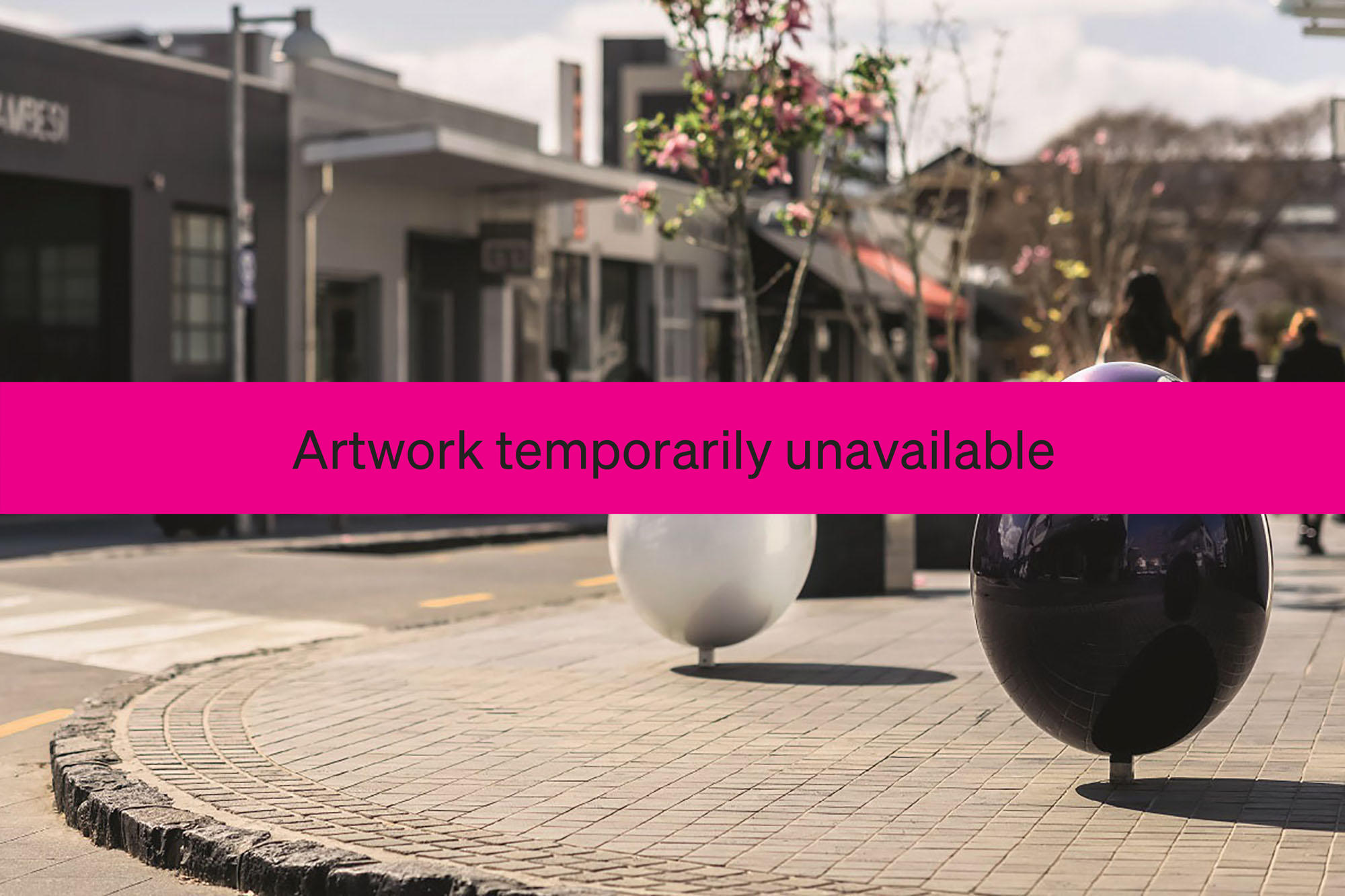 A pink 'unavailable' banner in front of two shiny egg shapes hovering on metal footpost just above pavement level on a street corner