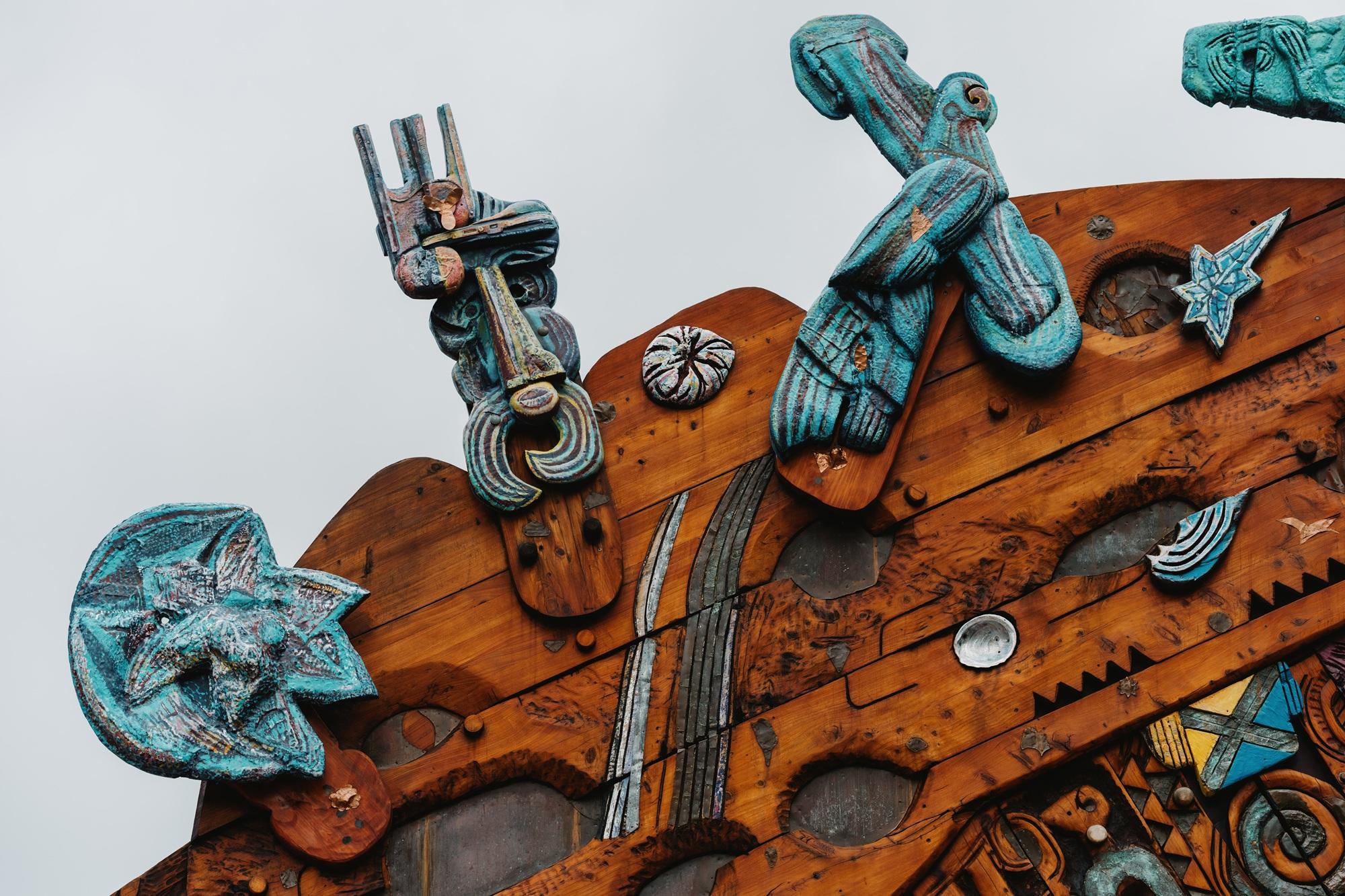 Detail view of the top of a colourful, carved wooden waharoa (gateway)