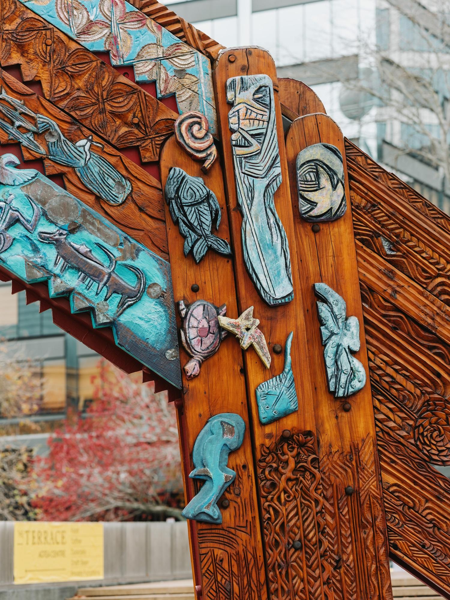 Detail view of the side of a colourful, carved wooden waharoa (gateway) in Aotea Square