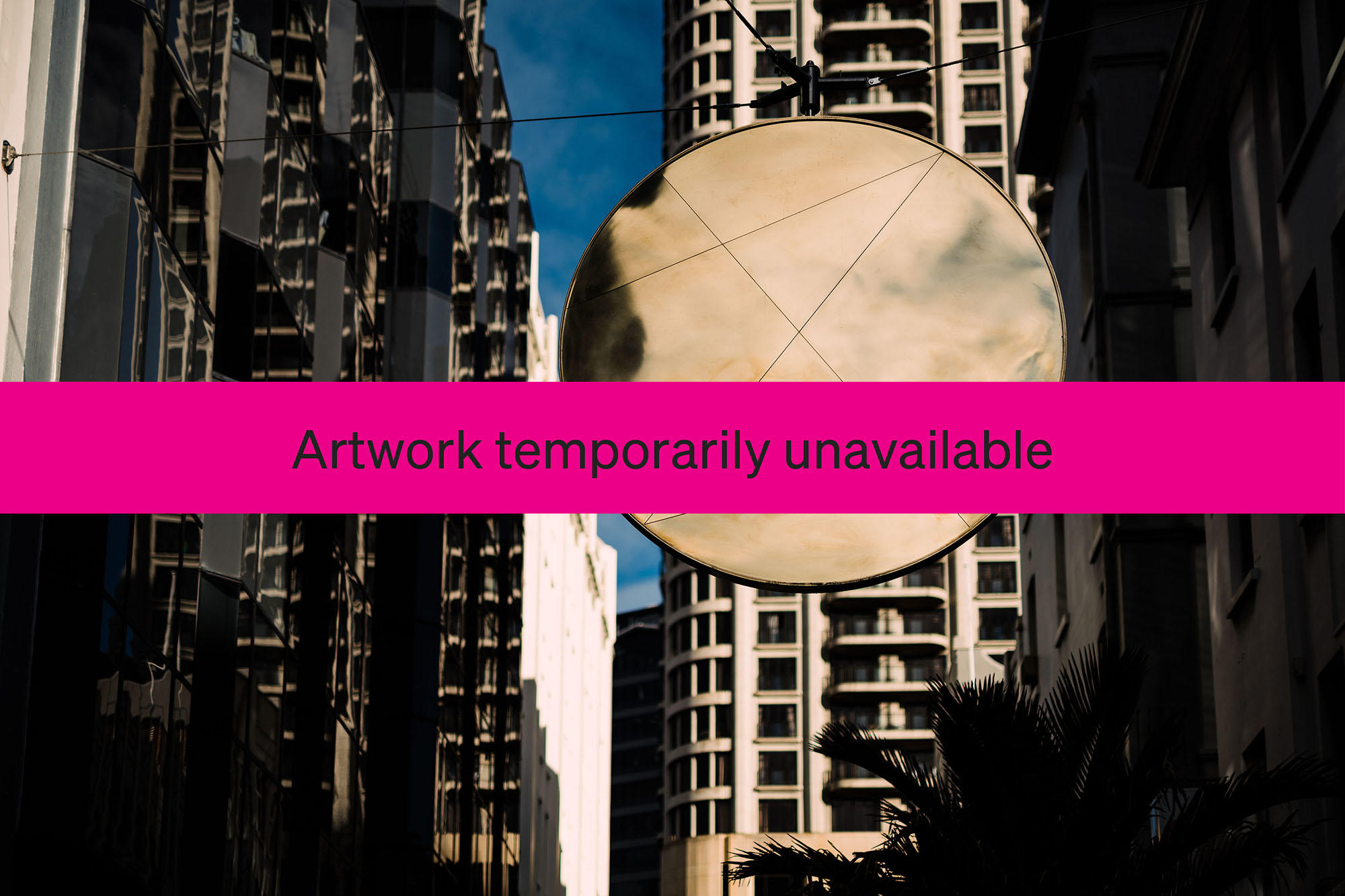 A giant round mirror suspended between buildings with a pink banner across it which says it is temporarily unavailable