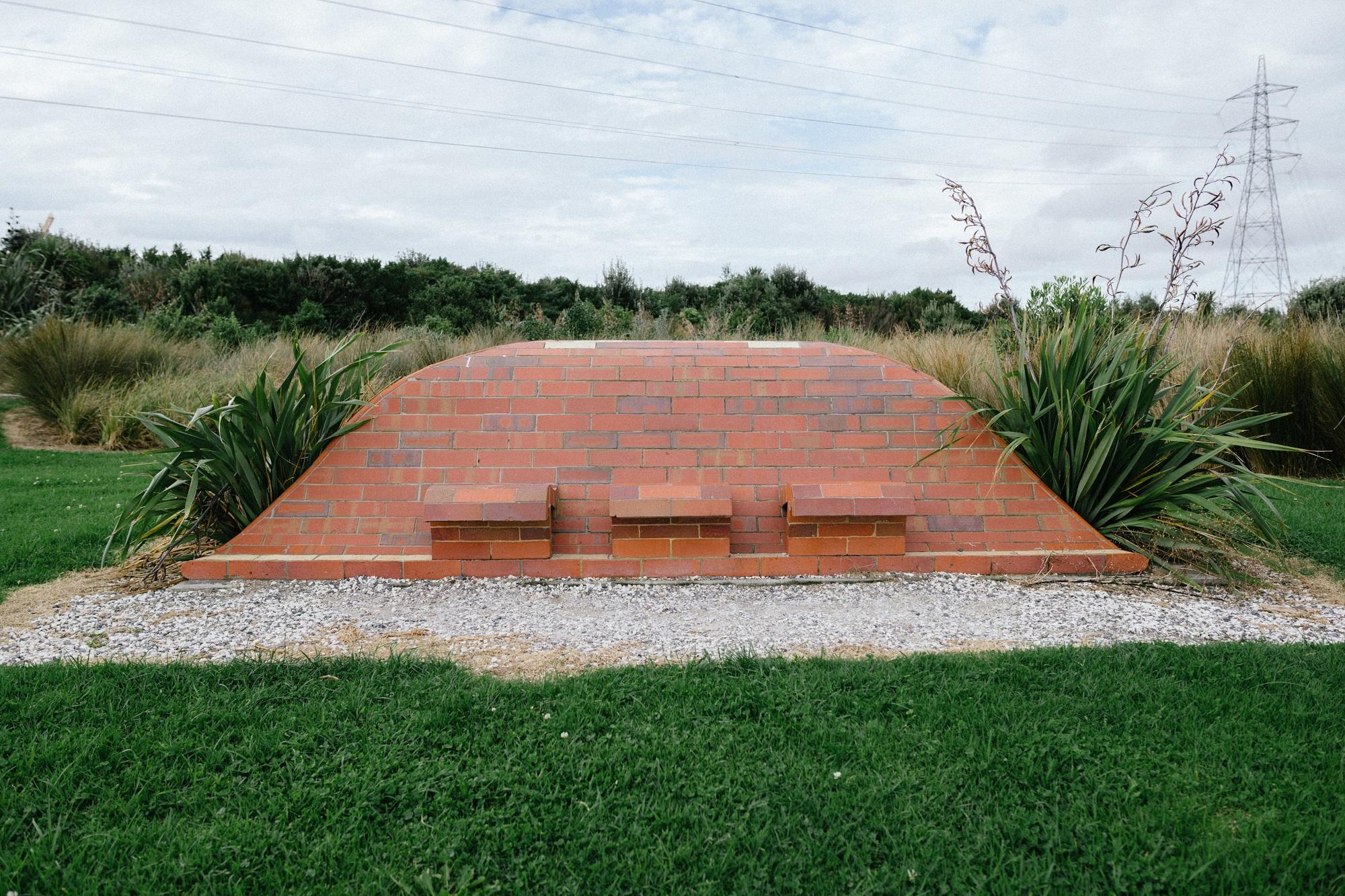 Rear view of a brick sculpture in the shape of a wave showing seating
