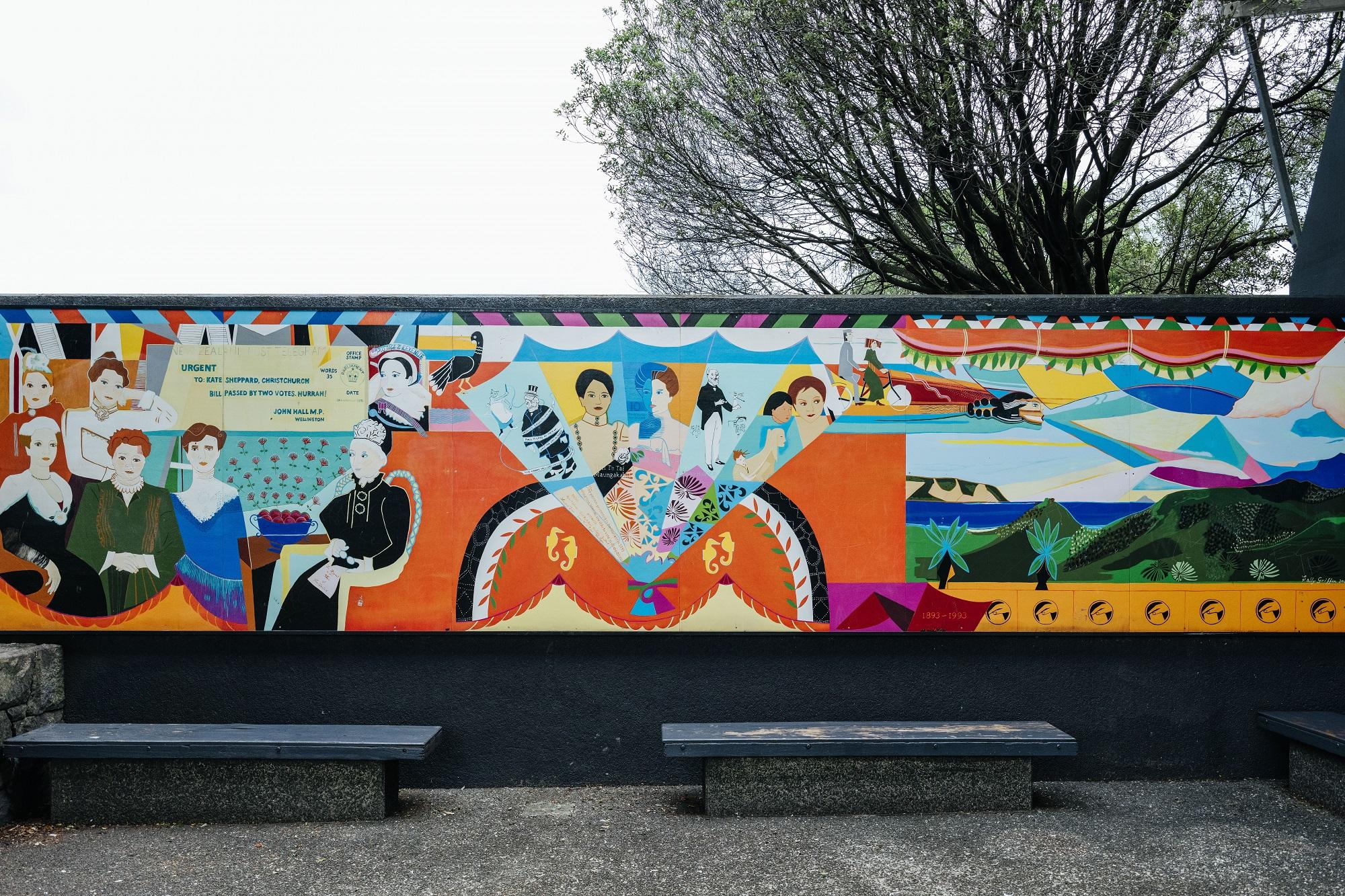 A colourful mural in three parts on a black wall